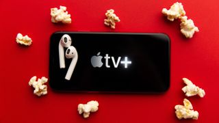 Apple TV Plus logo on phone surrounded by popcorn