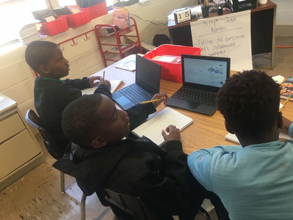 Three boys work on laptop computers