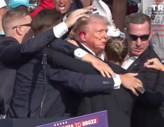 A screen grab captured from a video shows Republican presidential candidate former President Donald Trump appears to be injured after gunshots were reported as he is rushed offstage during a rally on July 13, 2024 in Butler, Pennsylvania.