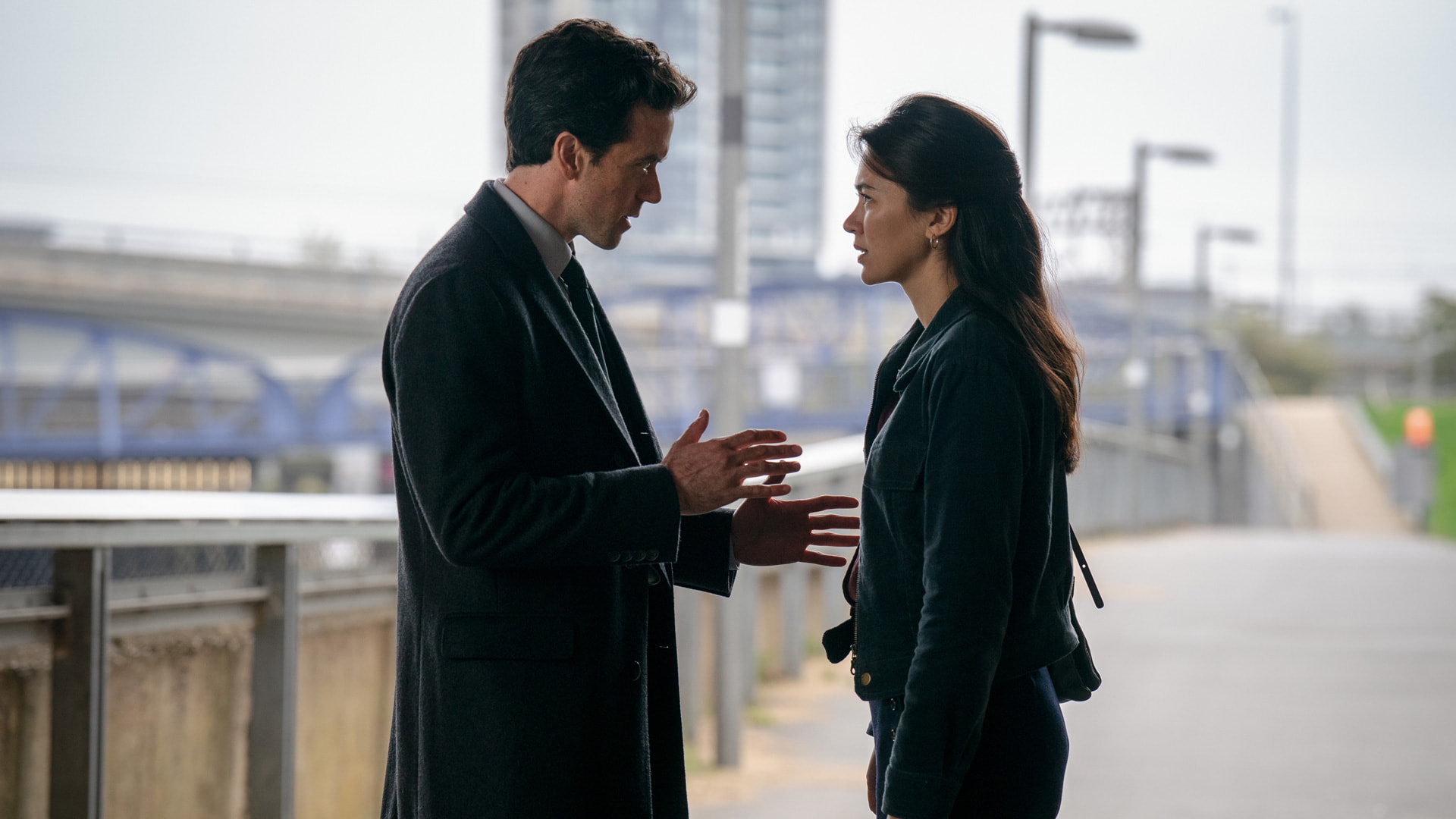 a man and woman talking on a bridge