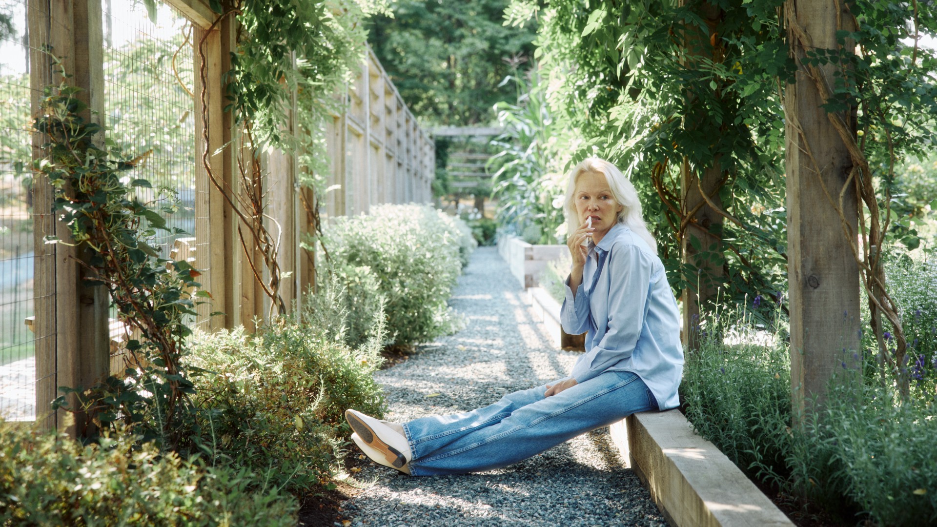 Pamela Anderson applying Sonsie Basic Balm in a garden. 