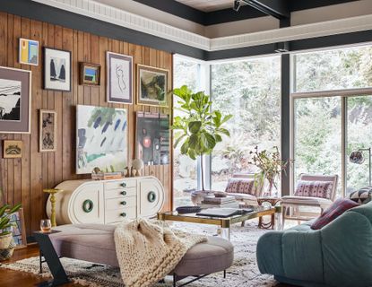 An eclectic living room with a gallery wall against a wood-clad wall
