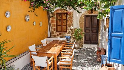 greek garden ideas – yellow courtyard with pergola and dining set
