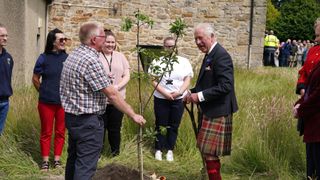 King Charles III plants a tree to commemorate the centenary of the estate becoming a public park during his visit to Kinneil House