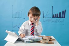 Young boy, talking on the phone, taking notes, money and tablet on the table