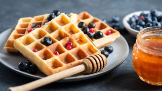 stack of waffles with blueberries and honey