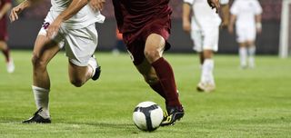 Soccer players run after a soccer ball.