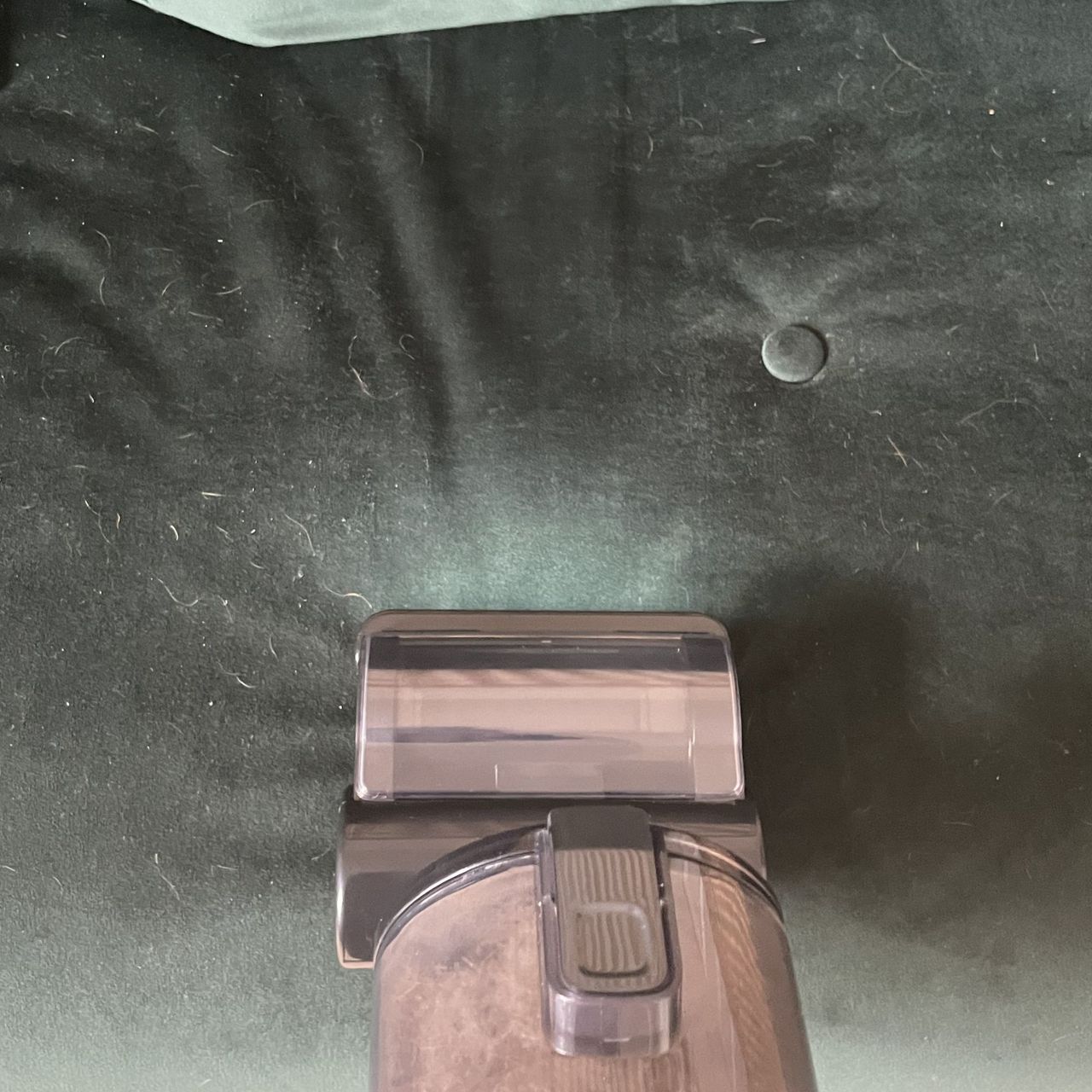 Using the pet tool of the Hoover HF3 Pet DynamicClean Cordless Vacuum on a green sofa bed