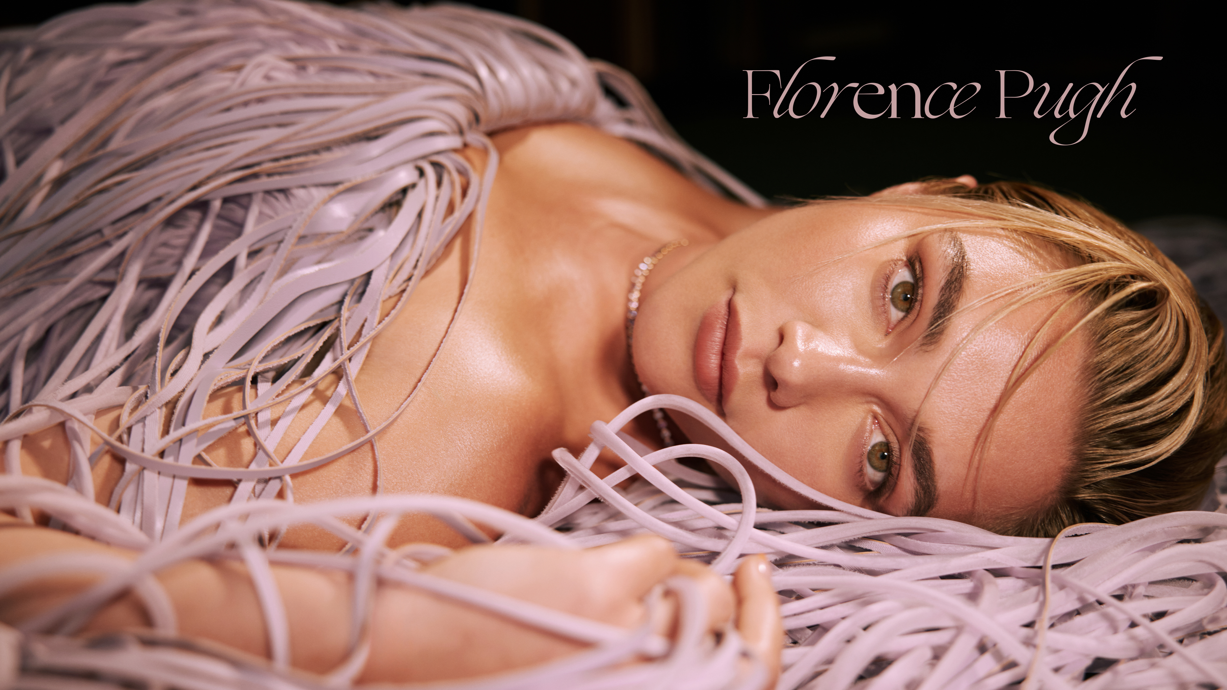 Florence Pugh laying down in a lilac leather fringe dress by Proenza Schouler. 