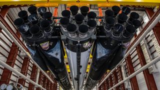 the 27 engines of a spacex falcon heavy rocket are seen up close inside a hangar.