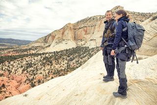 Bear Grylls stands on a rock with Natalie Portman