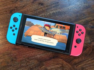 Nintendo Switch with Neon Red and Blue controllers displaying a fish from Animal Crossing