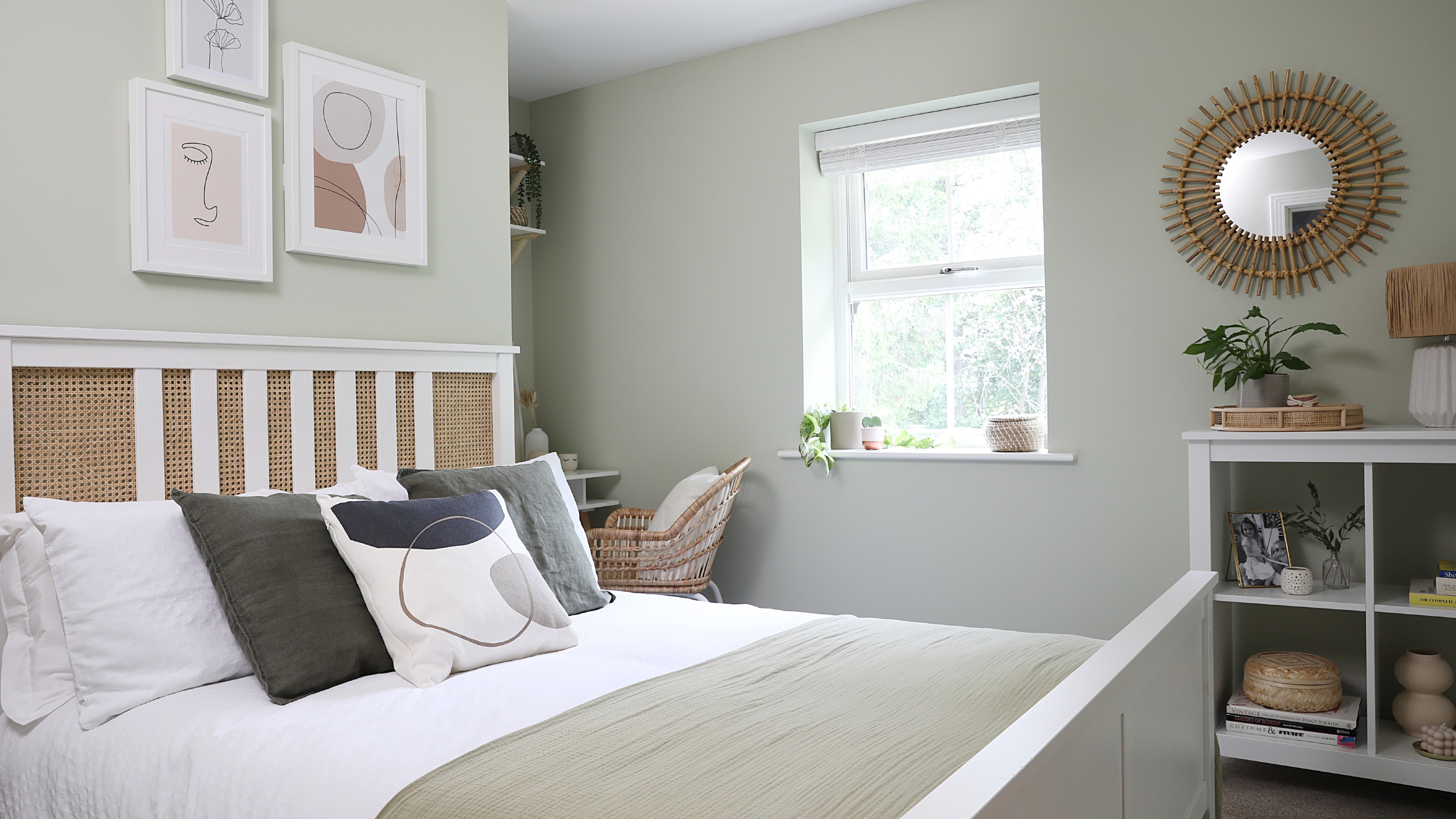 A light green-painted bedroom with a white bed and neutral accents