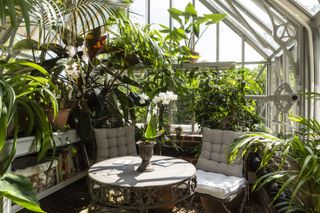 a greenhouse used as a garden room seating area
