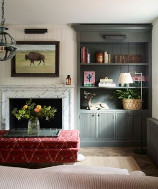 panelled living room with gray built in alcove shelving and a red ottoman