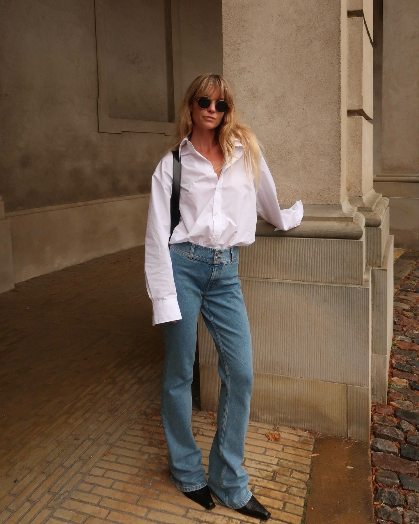 Influencer @_jeanettemadsen_ wears a white shirt with flared jeans and pointed-toe boots.