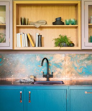Modern kitchen with blue cabinetry and copper-aged backsplash