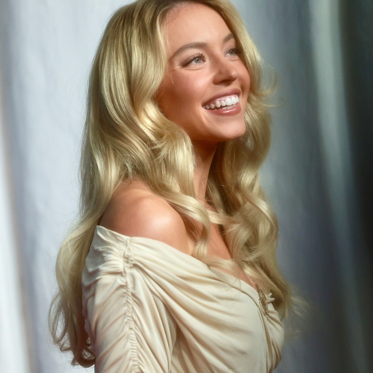 a white woman with blonde hair posing in front of a white backdrop