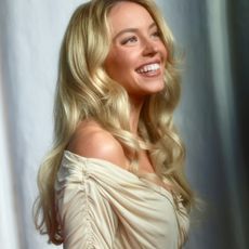a white woman with blonde hair posing in front of a white backdrop