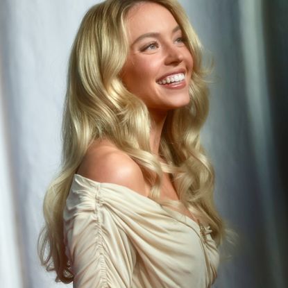 a white woman with blonde hair posing in front of a white backdrop