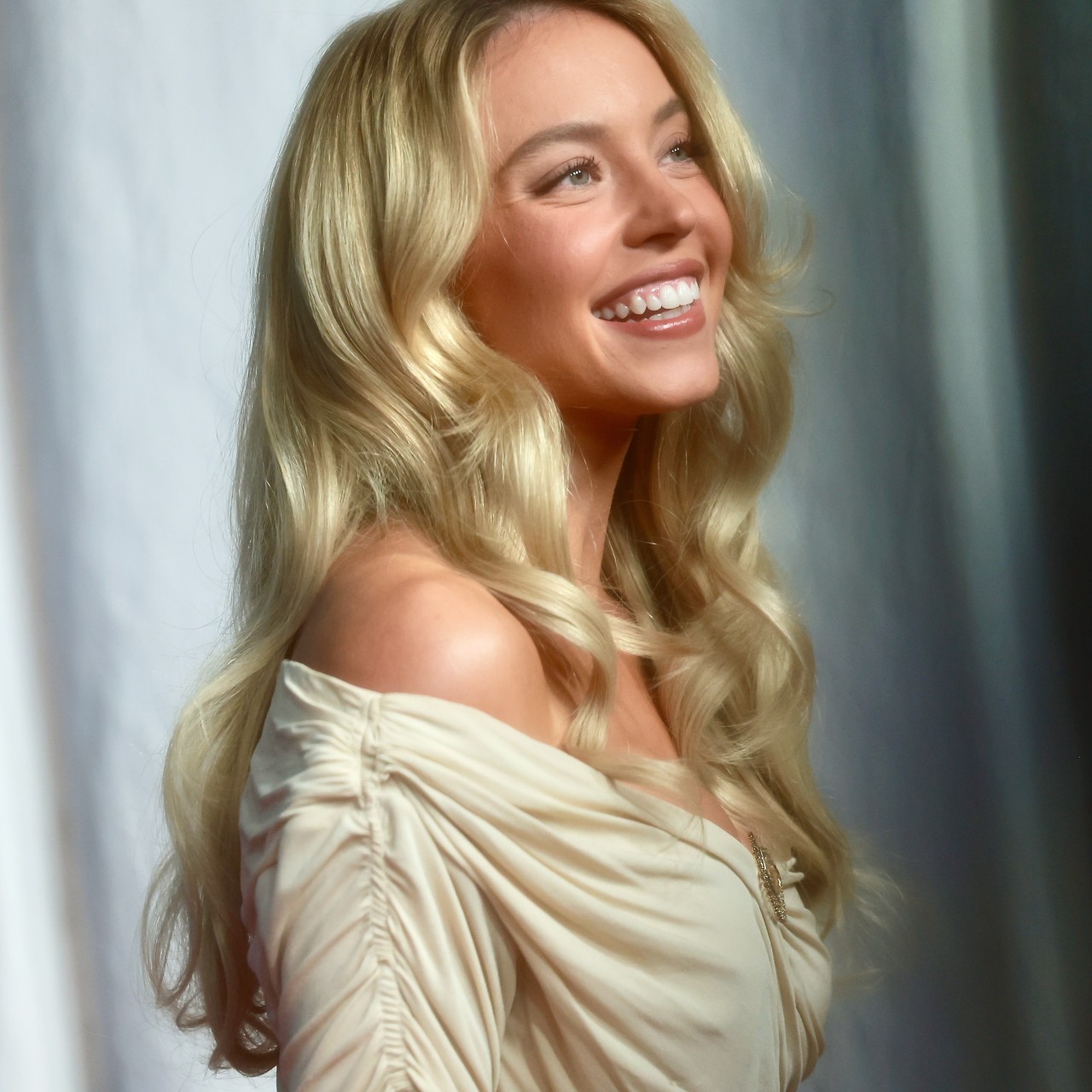 a white woman with blonde hair posing in front of a white backdrop