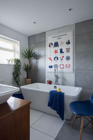 modern bathroom with a freestanding bath, grey wall tiles and a French print
