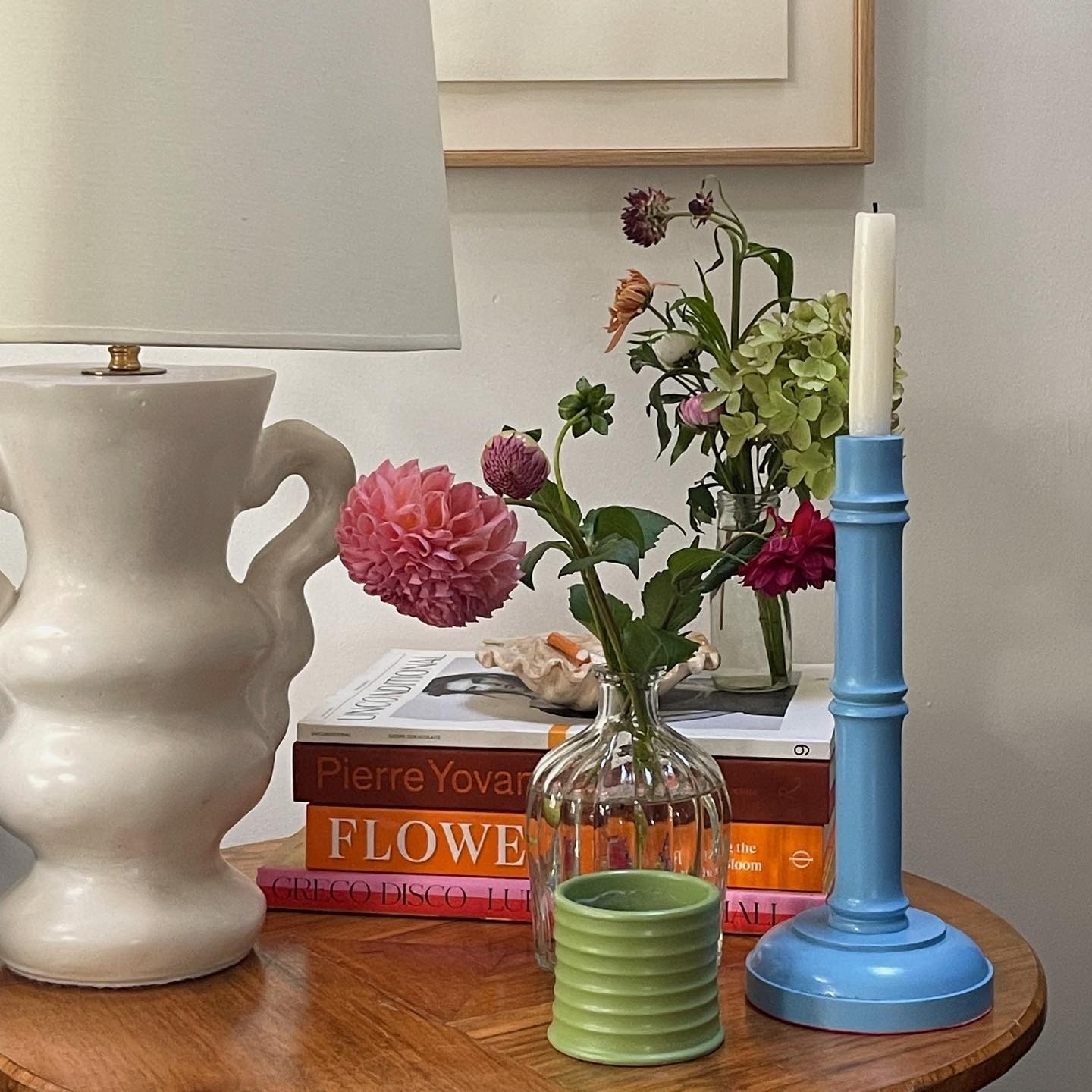 Photo of a side table with flowers, books, and candles 