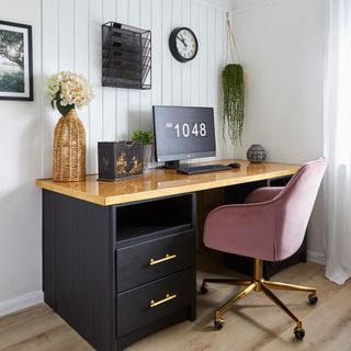 Home office with black desk, pink chair and panelling on wall
