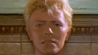 A close up of David Bowie with blonde hair, staring straight into the camera