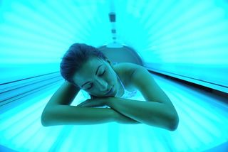 A woman lays on a tanning bed.