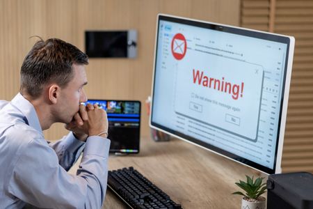 Businessman receiving phishing email warning on computer