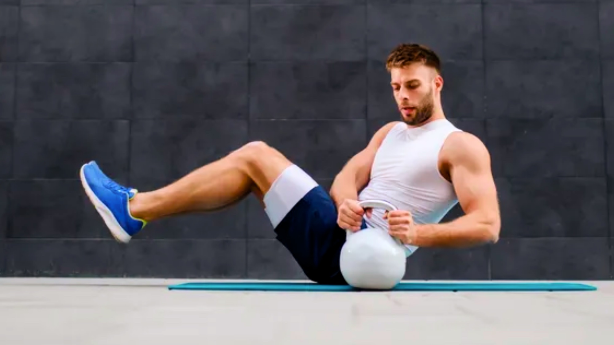 Muscular shirtless man workout with kettlebells in L Sit position