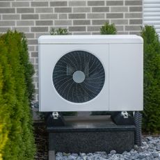 White heat pump outside on gravel