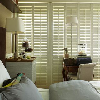 bedroom with shutter window and cushions on bed