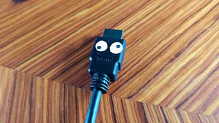 HDMI cable with cartoon eyes on woodgrain surface.