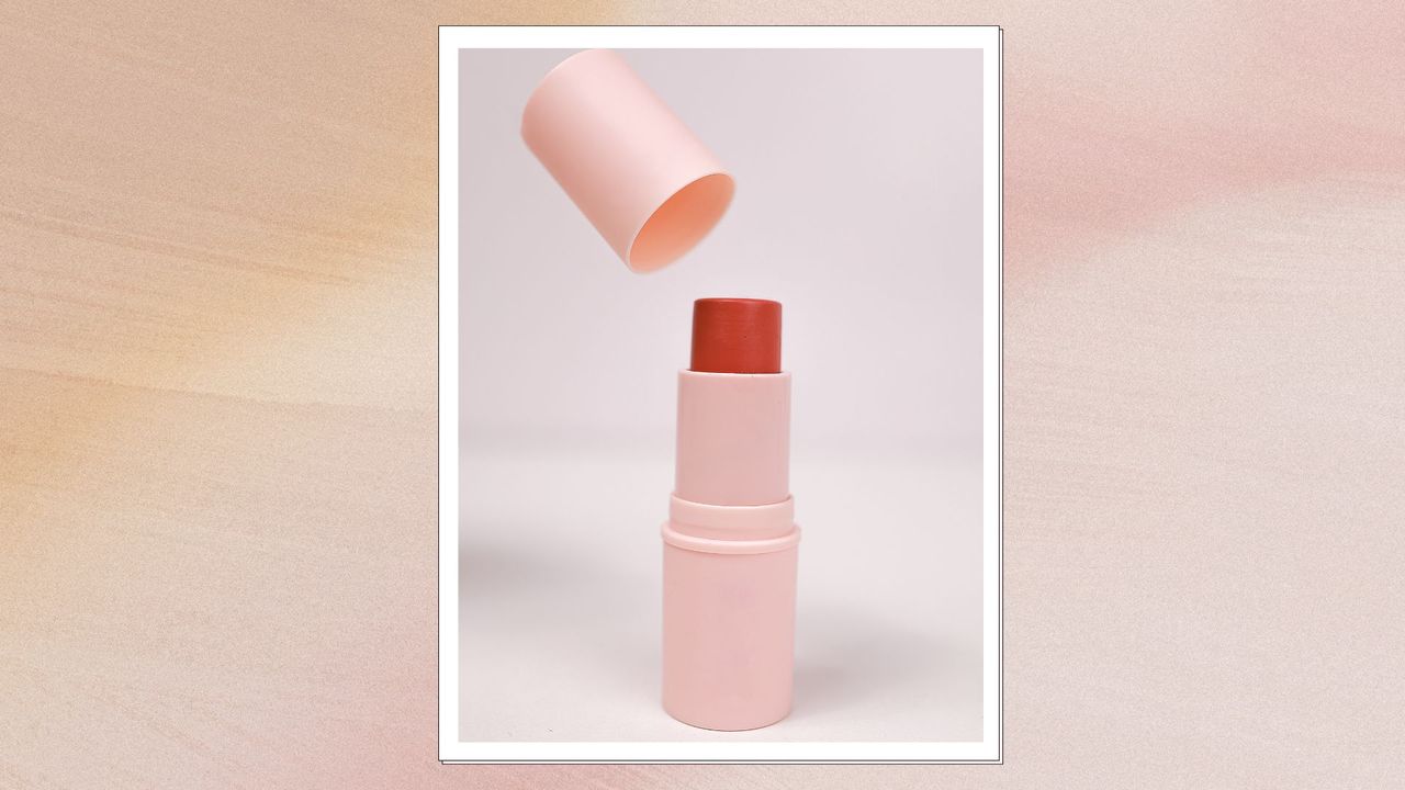 a beige backdrop with a picture of a makeup stick with it&#039;s lid off and the makeup twisted up