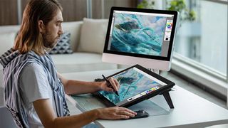 A man draws on one of the best Huion drawing tablets connected to a monitor