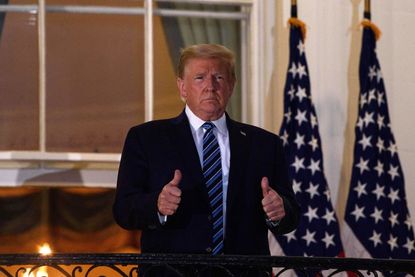 President Donald Trump gives two thumbs up from the Truman Balcony upon his return to the White House from Walter Reed Medical Center, where he underwent treatment for Covid-19, in Washington