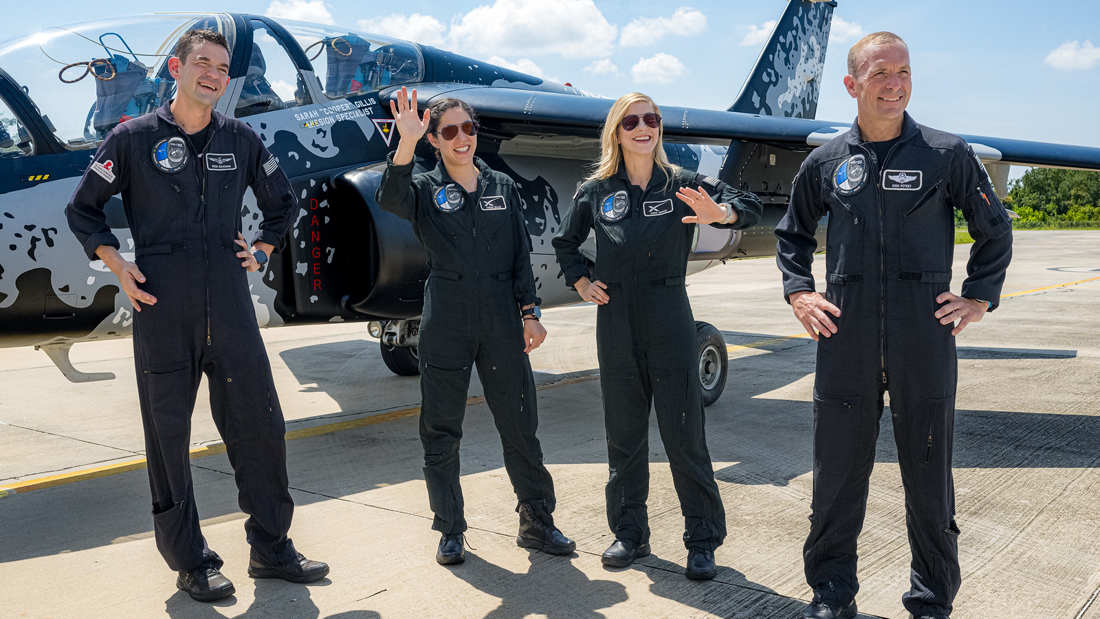 Four Polaris Dawn astronauts pose for photos in front of a jet plane.