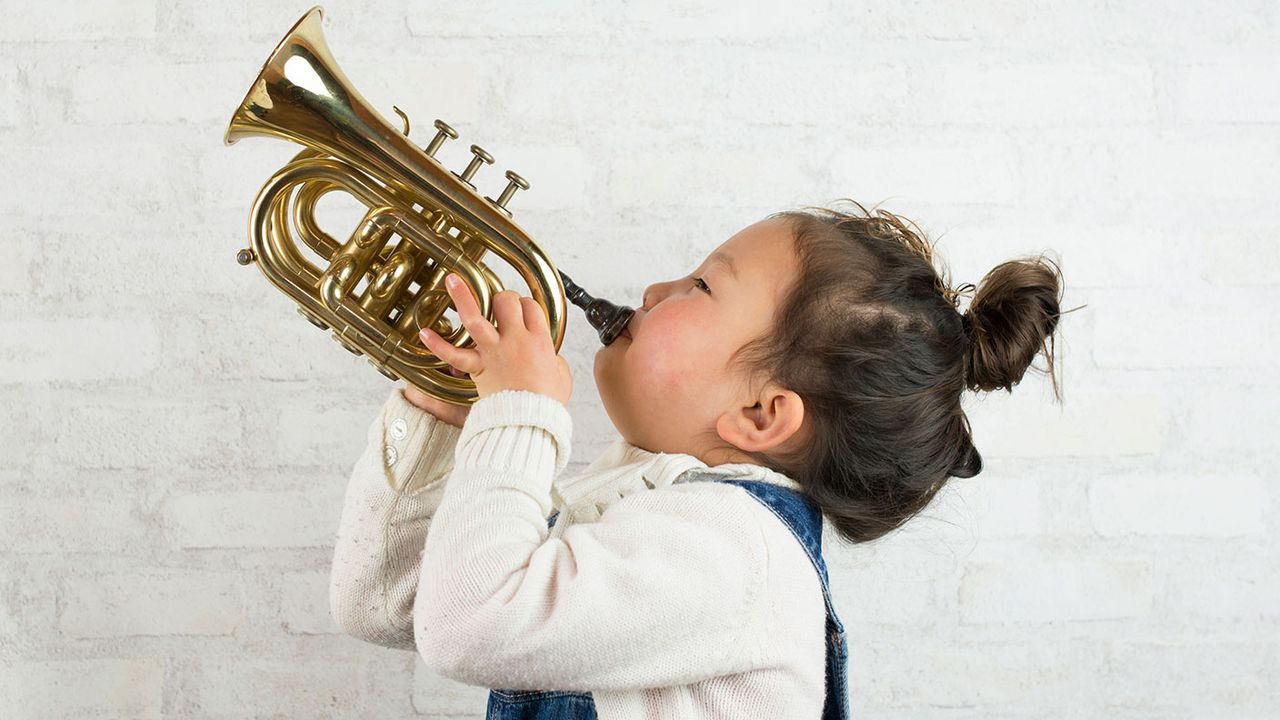 Small girl playing a trumpet ©