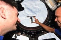 NASA astronauts Chris Williams holds his hand out, appearing to "hold" the Cygnus capsule from the ISS.