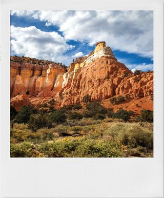 A red rock formation in the New Mexico desert against a blue sky