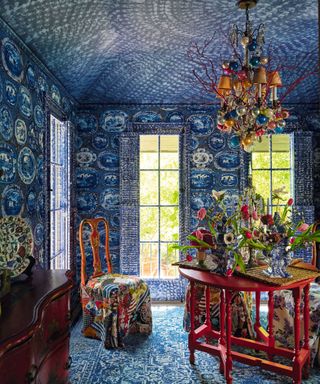 dining room with red table and upholstered red chair and blue mural on walls and ceilings