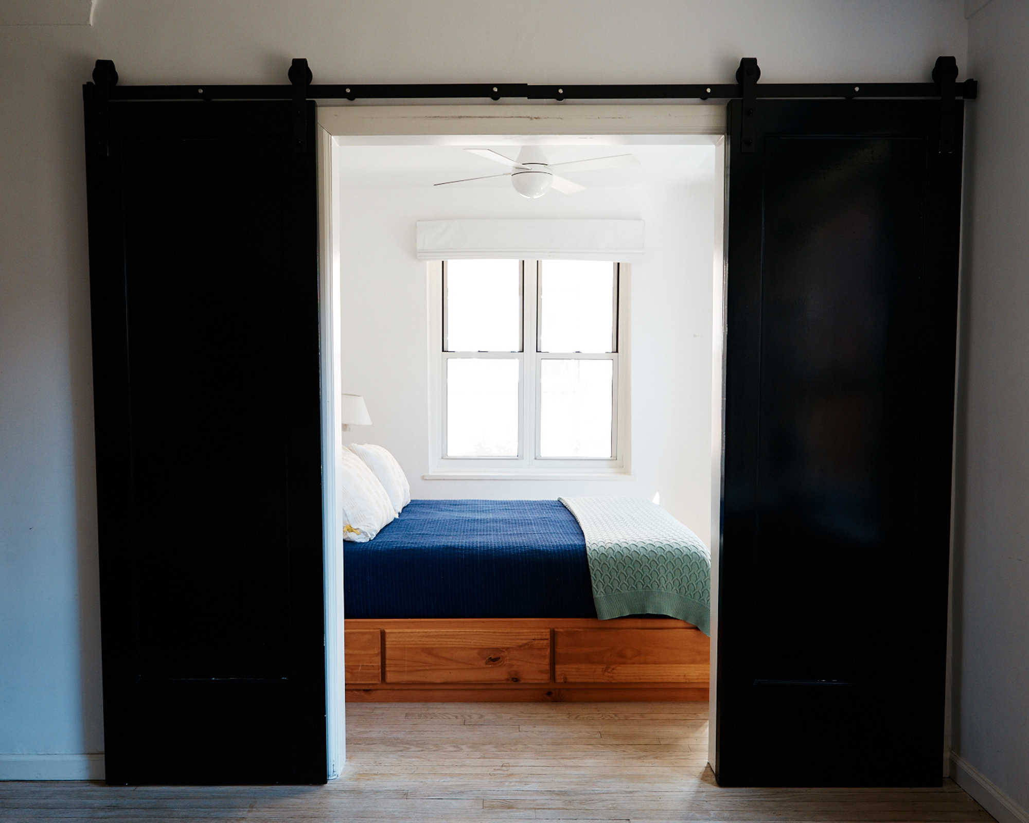 Sliding doors leading onto storage bed with wood drawers.