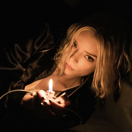 anya taylor joy as lucky hiding in a dark crawl space and lighting a match in a still from the apple tv show lucky