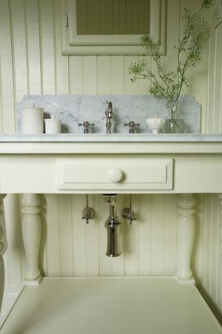 Upcycled cream bathroom vanity unit in bathroom with marble top, silver accents and wicker baskets