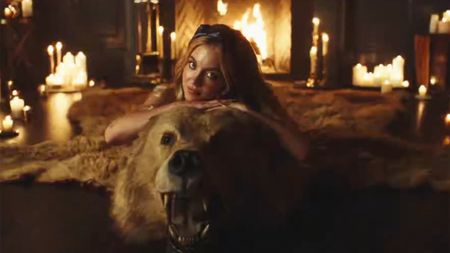 Sydney Sweeney lying on a bearskin run next to a roaring fire with candles lit all around in Euphoria HBO.