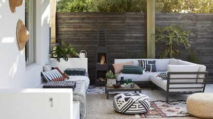 A backyard with outdoor furniture including outdoor sofa with upholstered outdoor cushions and outdoor rug