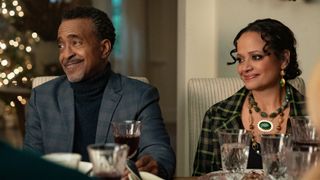 Tim Meadows as Stan and Judy Reyes as Margaret sitting at the Christmas dinner table and smiling in Our Little Secret.