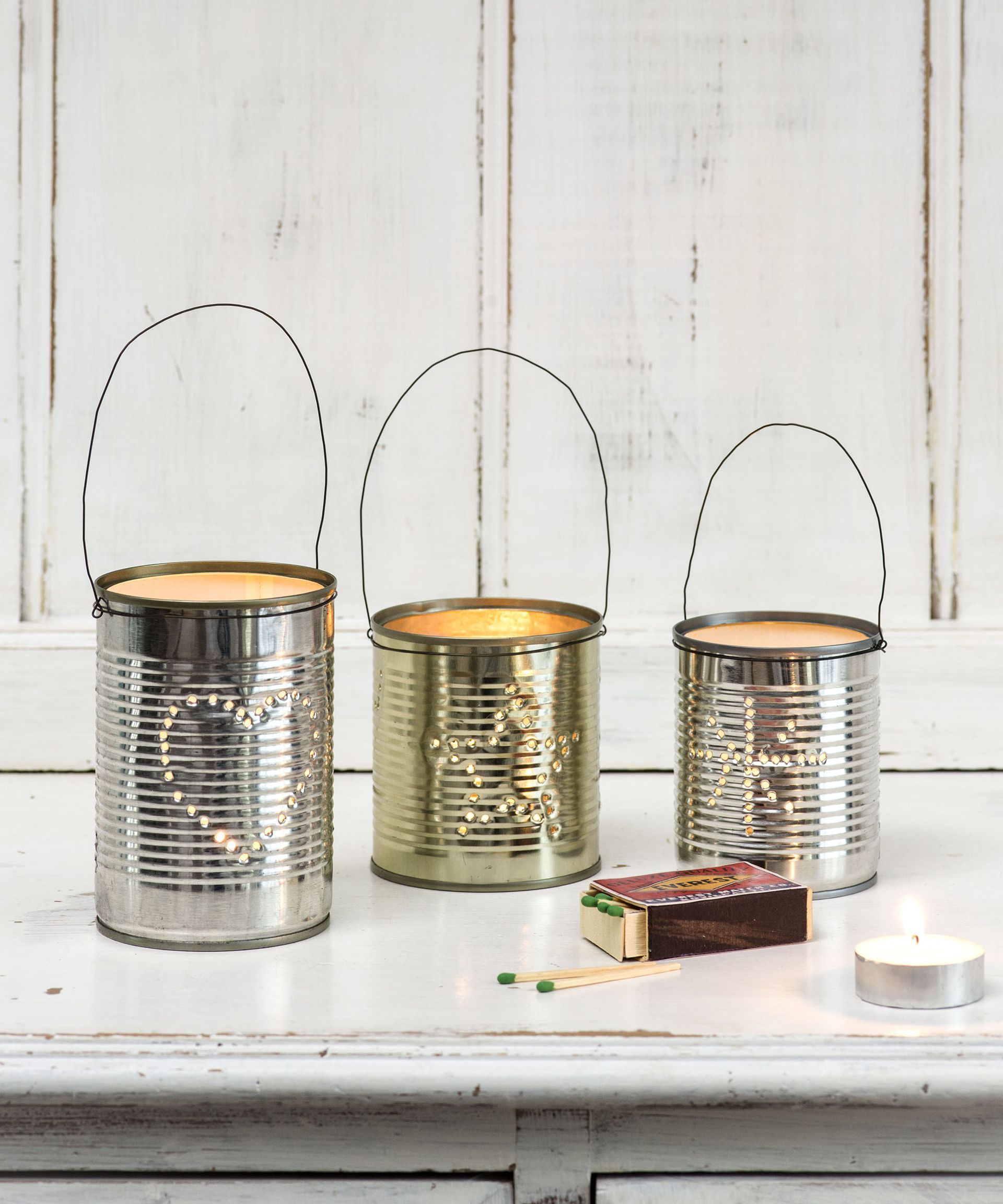 Upcycled tin can lanterns on table next to matches